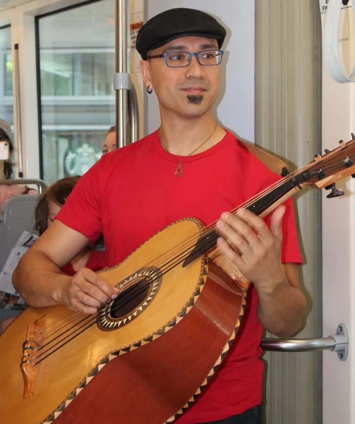 Playing a guitarrón standing on a crowded light-rail train
