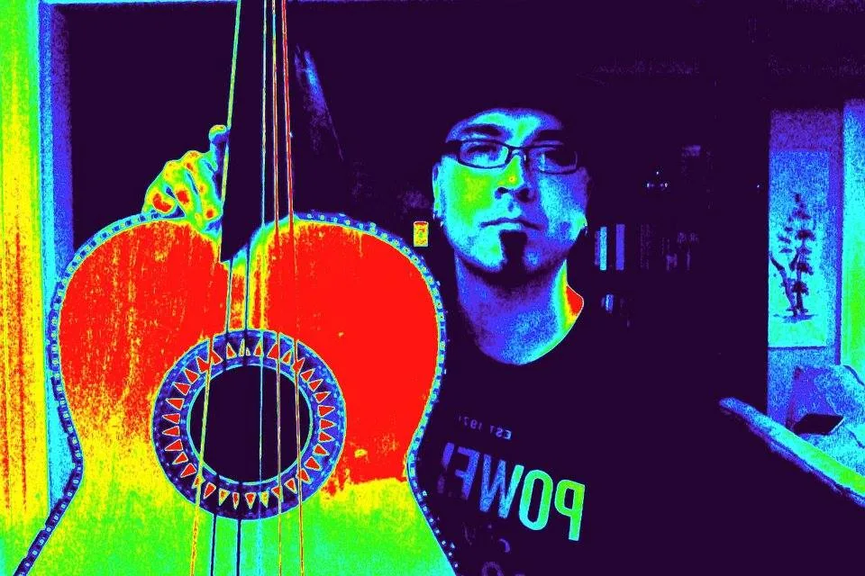 A guitarrón held up beside Jason Krivo Flores, the whole image rendered in psychedelic false color